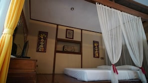 Une chambre à coucher comprenant un lit, une table de chevet, un miroir et des œuvres d’art accrochées au mur.