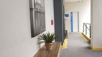 Un couloir avec un pot de fleurs, un banc en bois, une porte et un escalier.