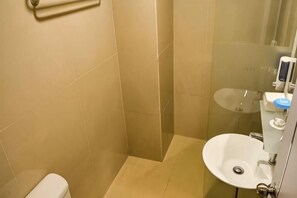Une salle de bain équipée de toilettes, d’un lavabo et d’une douche à parois de verre.
