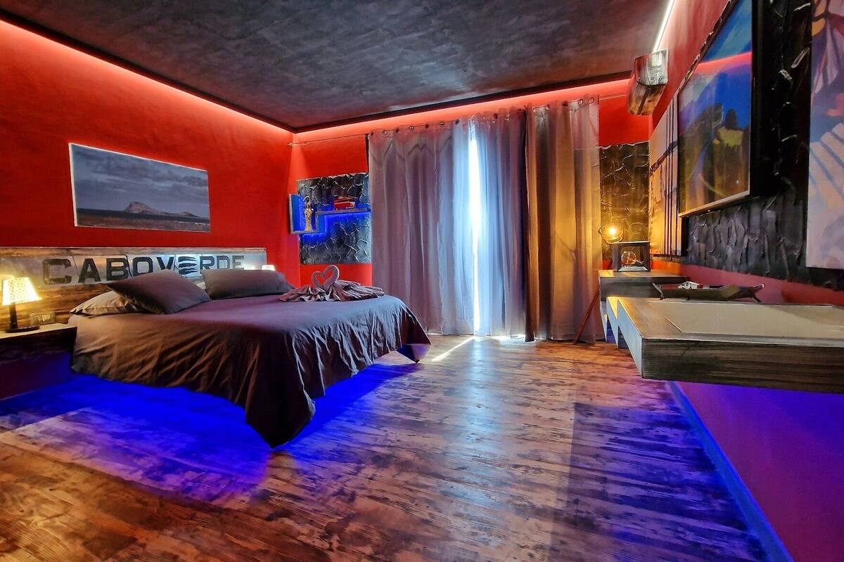 A modern hotel room with a bed, a desk, and a large window with curtains.