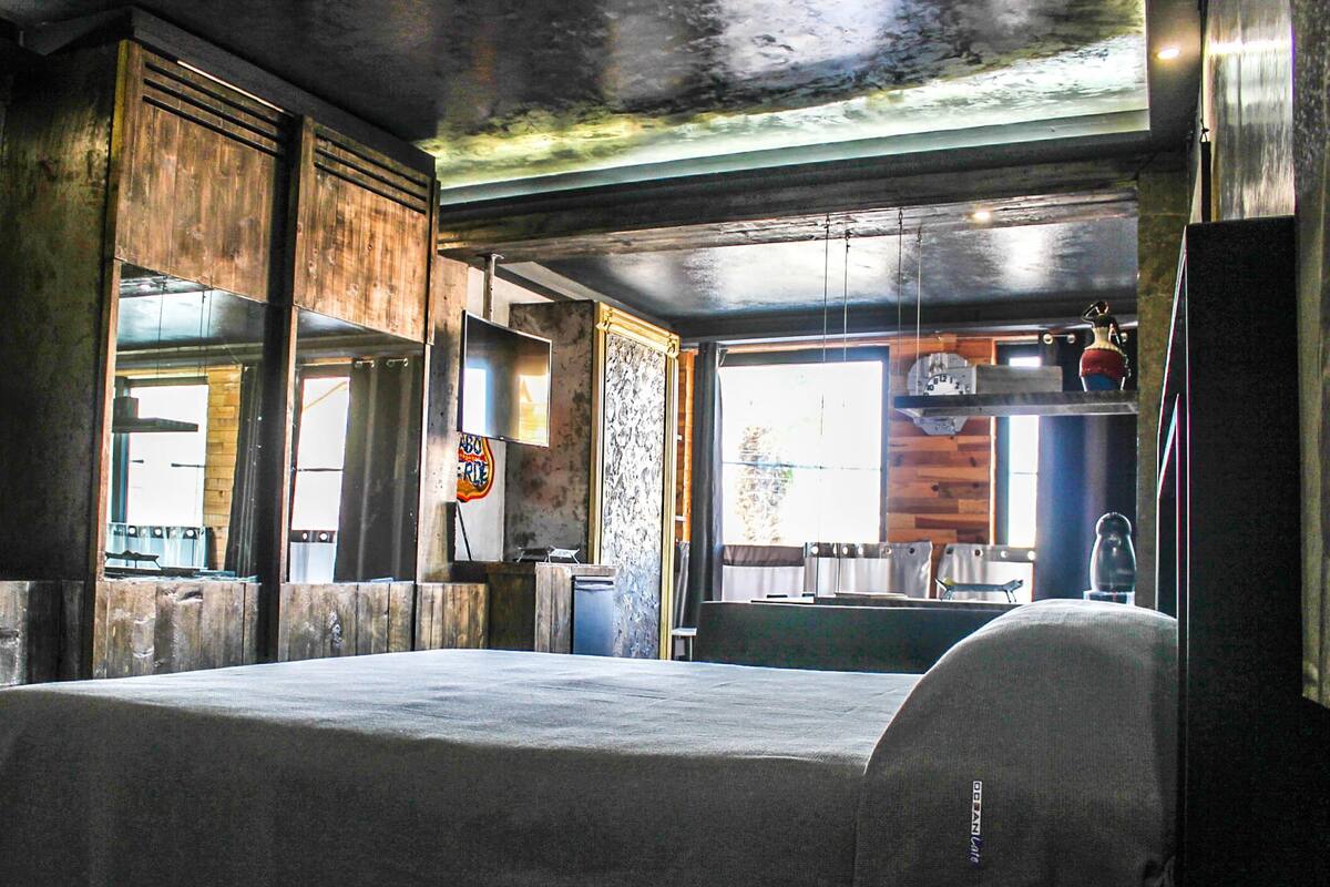 A room with a bed, wooden walls, a window, and a clock.