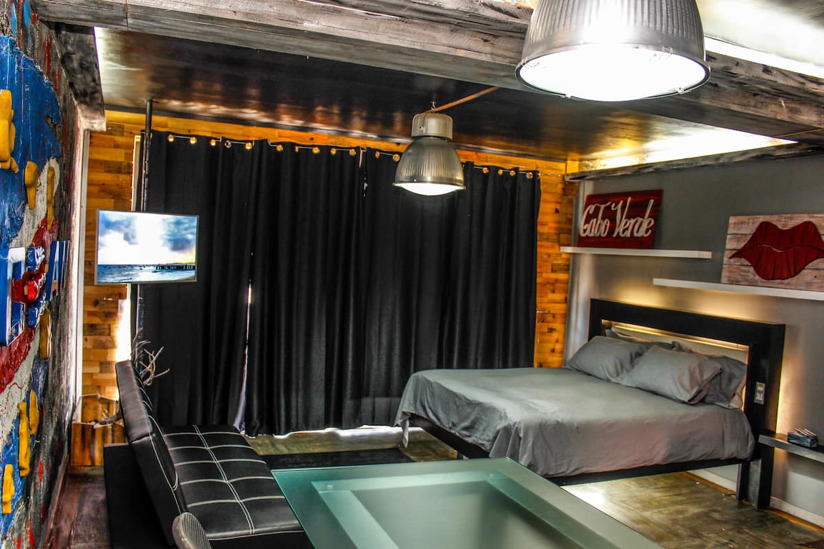 A modern bedroom with a bed, a TV, and a unique wall art piece.