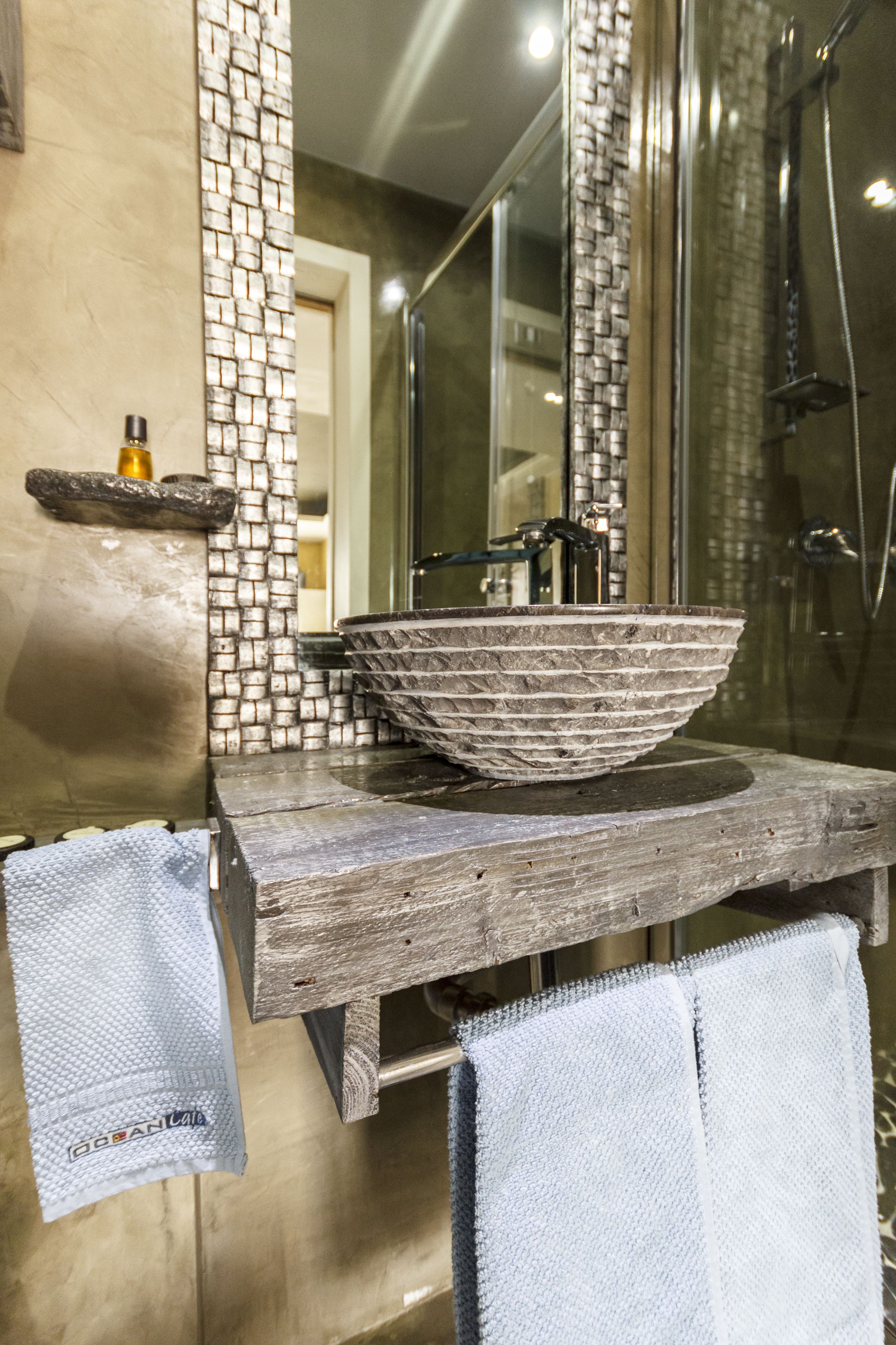 A bathroom with a stone sink, a mirror, and a shower.