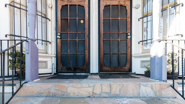 A stone staircase leading to a wooden door with a grid pattern.