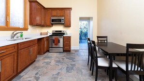 A kitchen with wooden cabinets, a stove, and a microwave. There is a dining table with chairs.