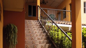 Una escalera con baldosas estampadas, barandilla de metal y una planta colgante.