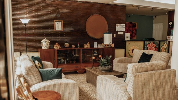 Un salón acogedor con sofás a rayas, una mesa de centro de madera y una pared de ladrillo.
