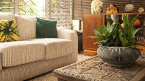 Una sala de estar con un sofá, una mesa de centro estampada y una planta en maceta.