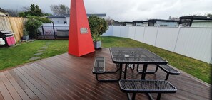 A wooden deck with picnic tables and a red pillar.