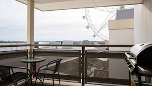 En balkon med grill, stole og udsigt til et pariserhjul og bygninger.