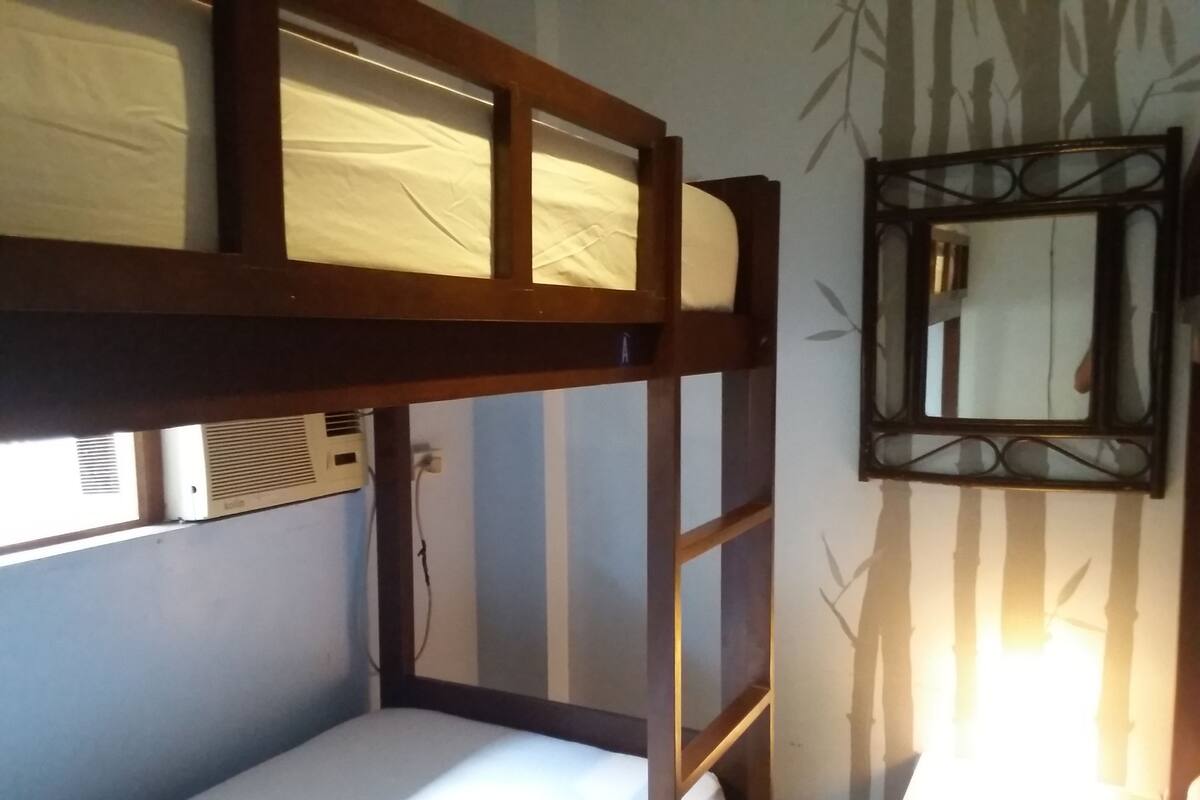 Una cama literera con ventana y aire acondicionado.