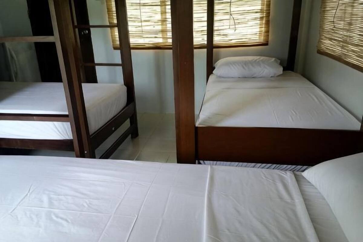Una habitación con tres literas de madera, cada una con ropa blanca de cama.