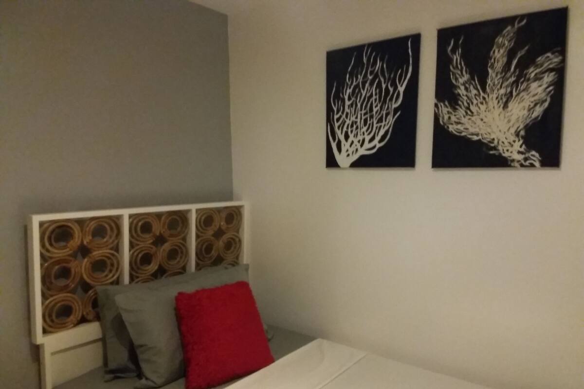 Un dormitorio con cama, cabecera con diseños circulares y dos obras de arte en las paredes.