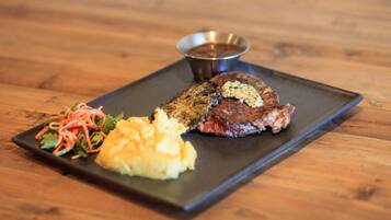 A steak with a side of mashed potatoes and a salad on a black plate.