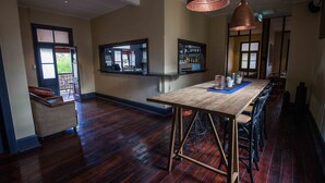 Una habitación amplia con una mesa de madera, taburetes de bar y un ventanal grande.