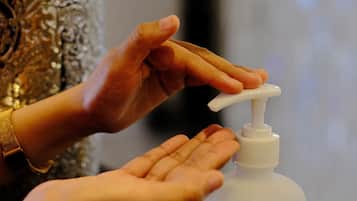 A hand dispensing sanitizer from a pump bottle.