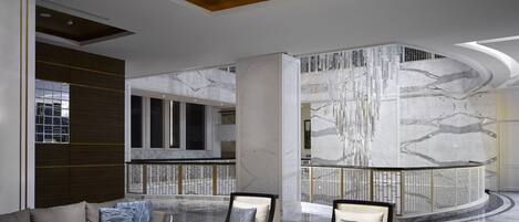 En rymlig entréhall med modern inredning, ett marmorgolv och en storslagen kristallkrona.