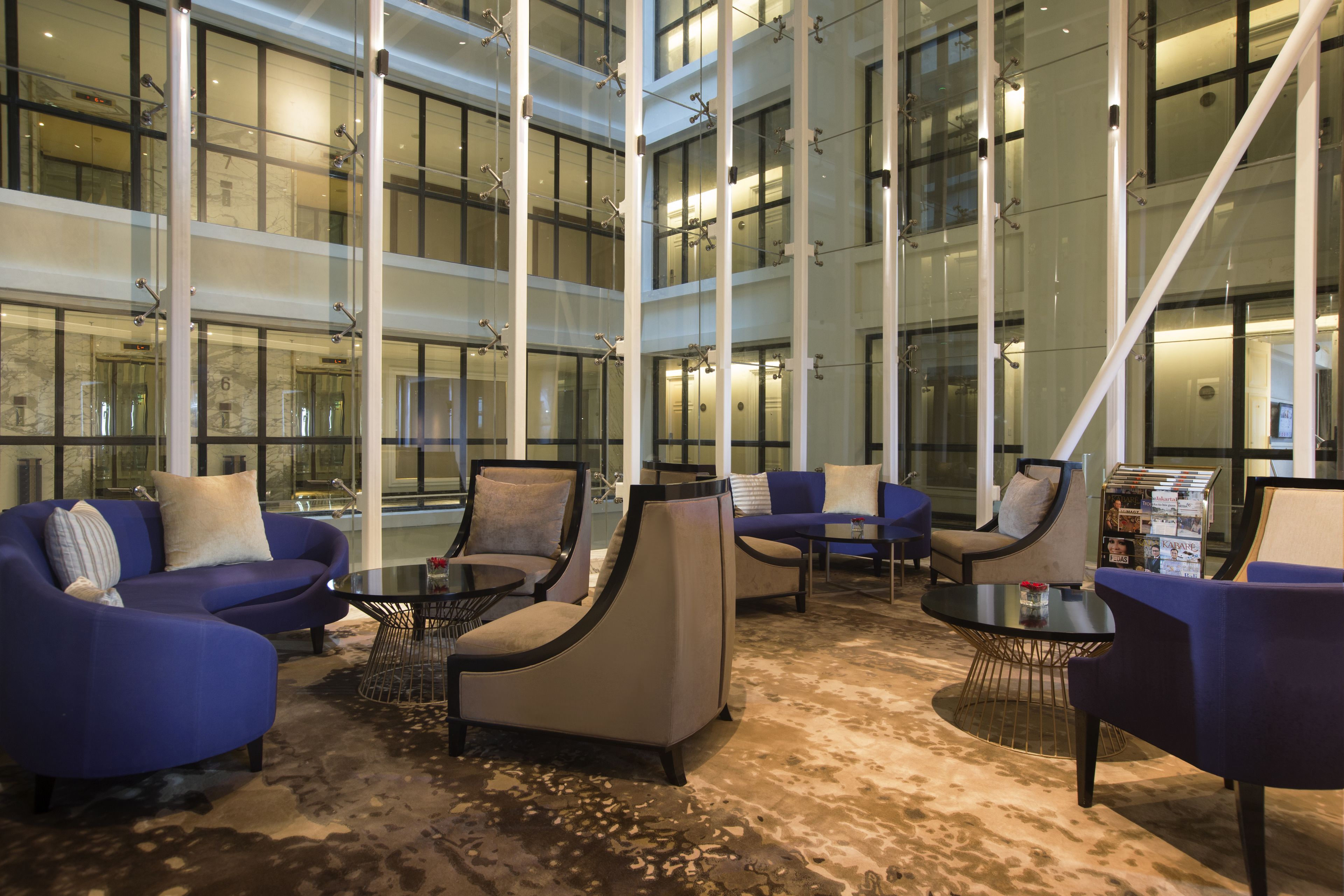 Eine geräumige Lobby mit mehreren Sitzbereichen, darunter Sofas und Sessel, die um einen zentralen Couchtisch angeordnet sind.