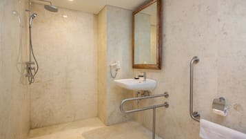 Un baño con ducha, lavabo, espejo y barra de apoyo.