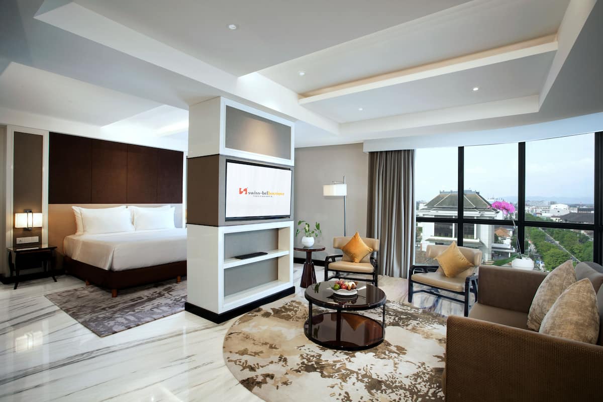 Ein modernes Hotelzimmer mit einem großen Bett, einem Sofa, einem Couchtisch und Blick auf die Stadt.