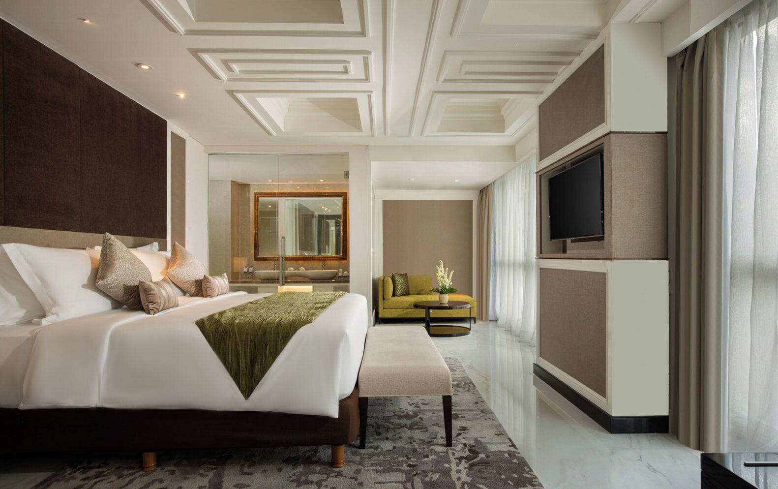 A modern hotel room with a large bed, a sofa, a TV, and a bathroom with a large mirror.