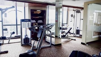 A gym with cardio machines, weightlifting equipment, and a mirrored wall.