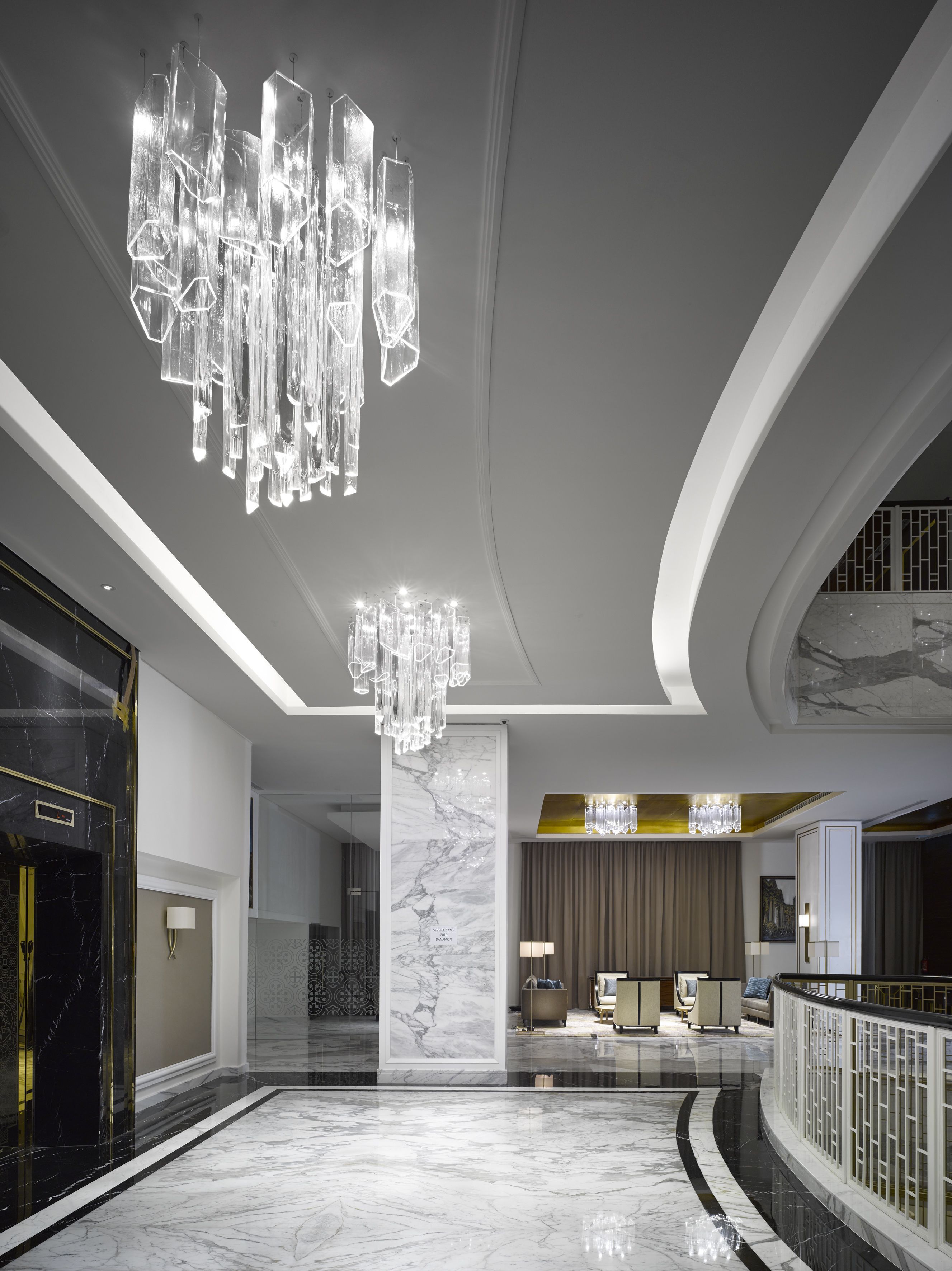 A spacious lobby with a marble floor, a large crystal chandelier, and a modern reception desk.