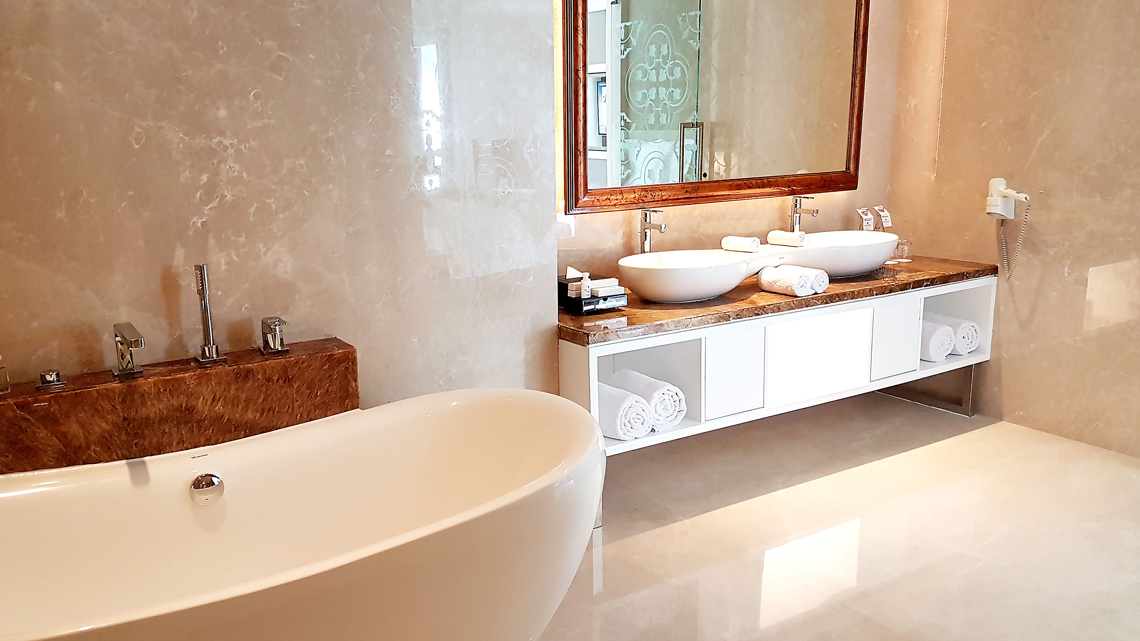 A modern bathroom with a freestanding bathtub, two sinks, and a vanity with storage.