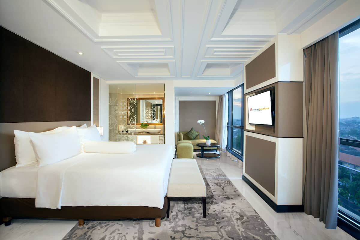 Ein modernes Hotelzimmer mit einem großen Bett, einem Fernseher und Blick auf die Stadt.