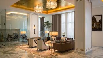 Eine großzügige Lobby mit Marmorboden, einer imposanten Chandelier und einer Sitzecke mit Sofas und Sesseln.