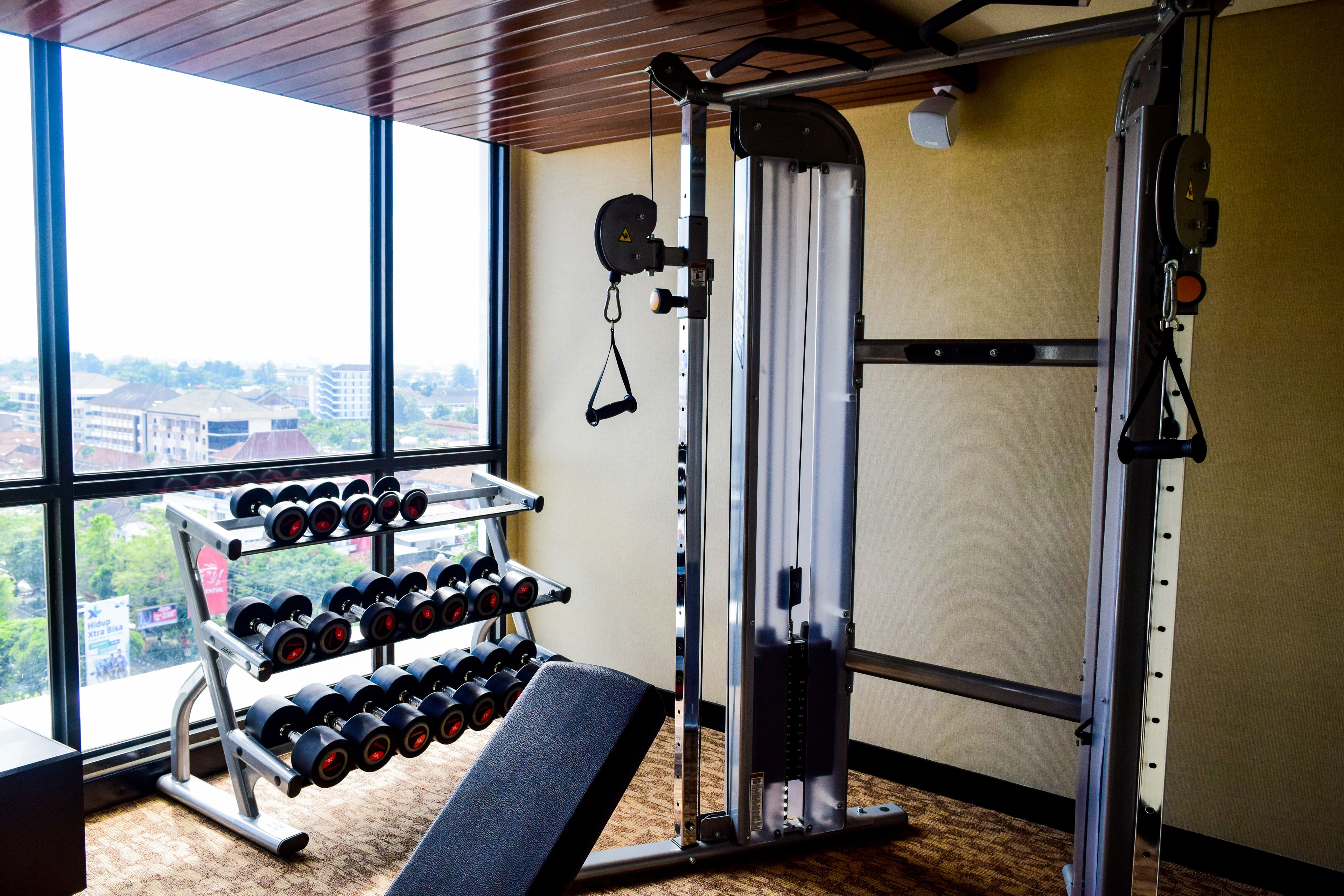 Un gimnasio con una banca, mancuernas y una máquina de poleas.