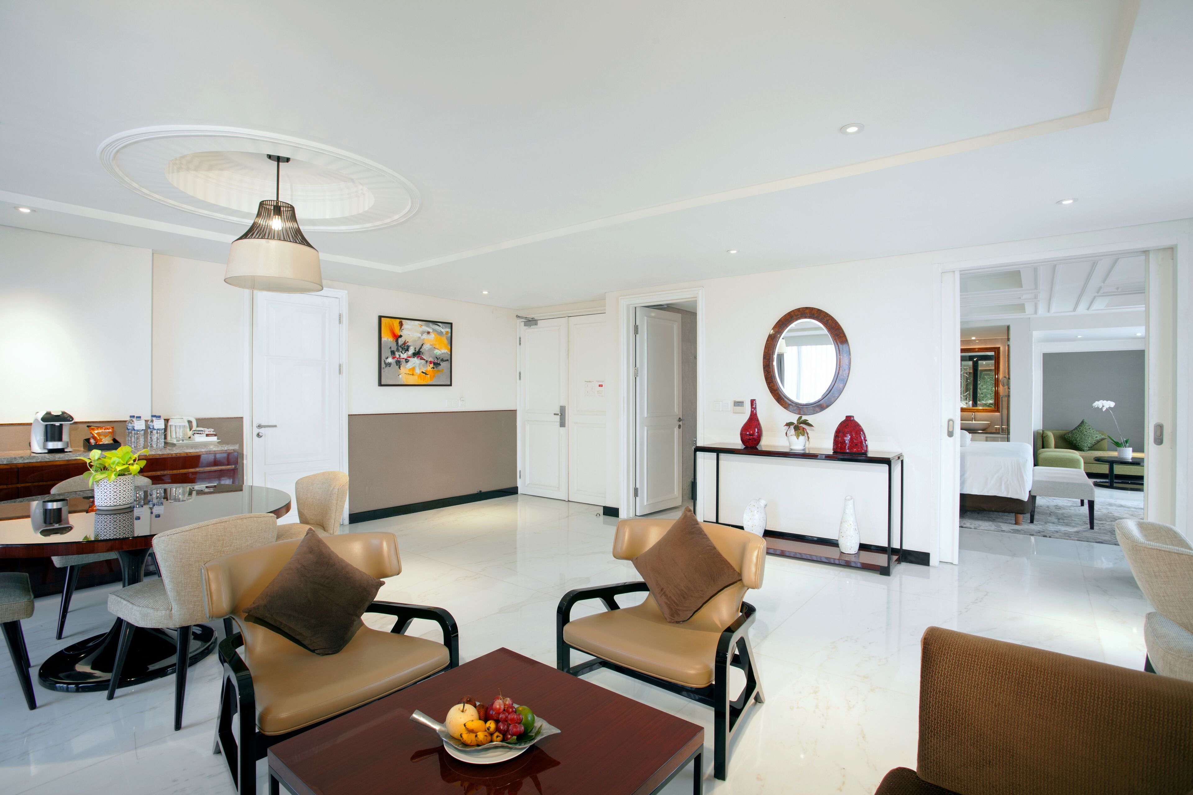 A modern living room with a dining area, featuring leather chairs, a coffee table, and a fruit bowl.
