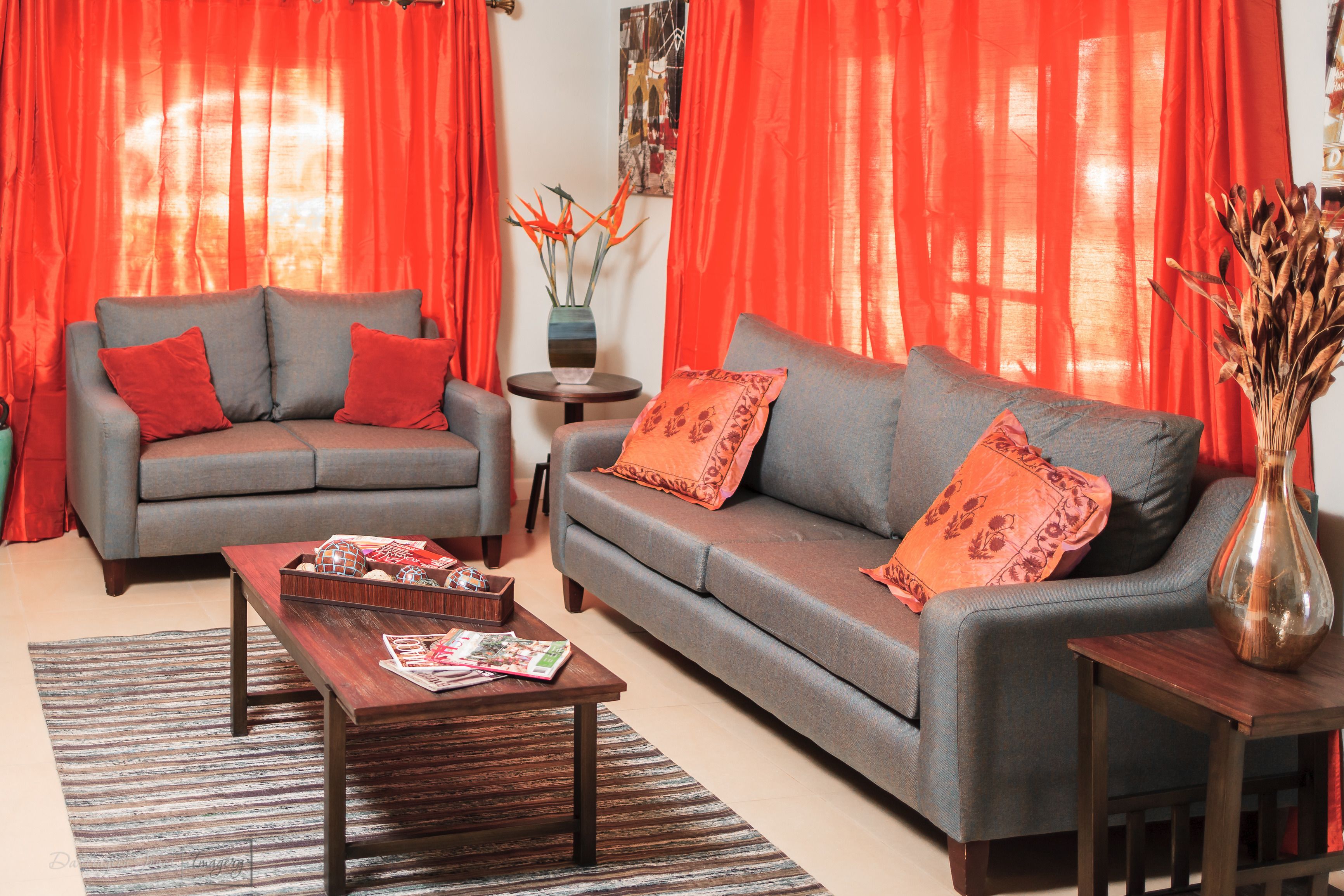 Una sala de estar con un sofá y un sillón grises, una mesa de centro de madera y una mesita auxiliar con un florero.