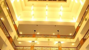 Um hall espaçoso com teto alto, vários níveis e uma área central aberta que dá acesso à receção.