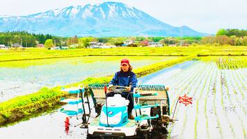 Una persona manejando una máquina agrícola impulsada por agua en un campo, con una montaña al fondo.
