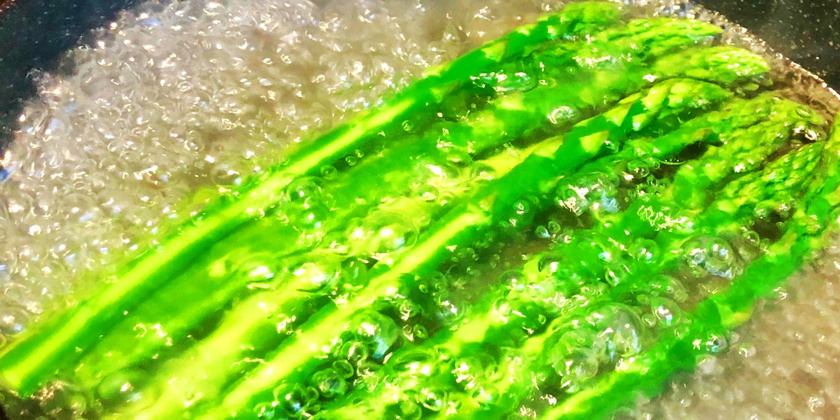 A close-up of green asparagus being cooked in a pot of boiling water.