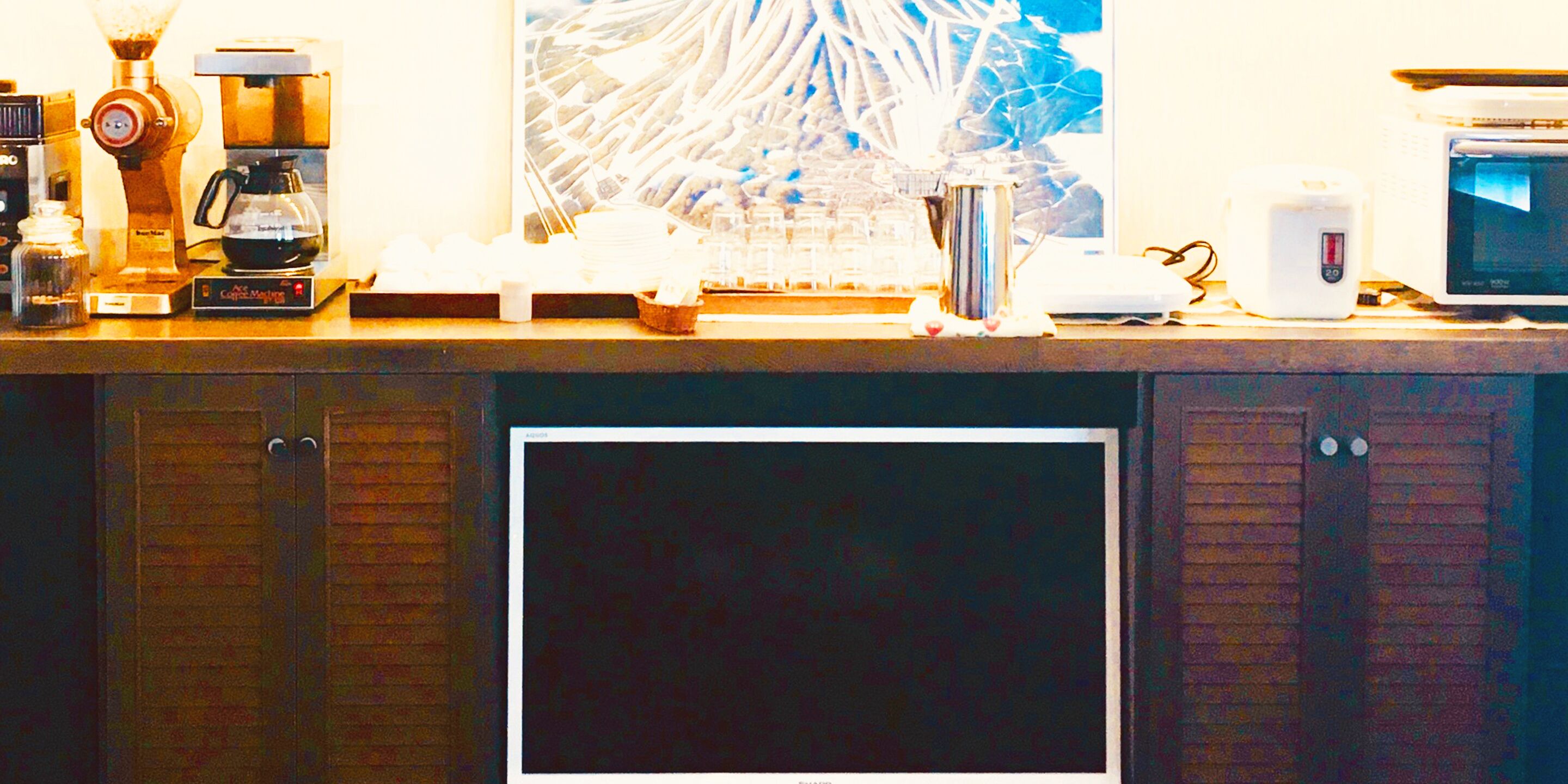 Una encimera de cocina con cafetera, microondas y refrigerador.