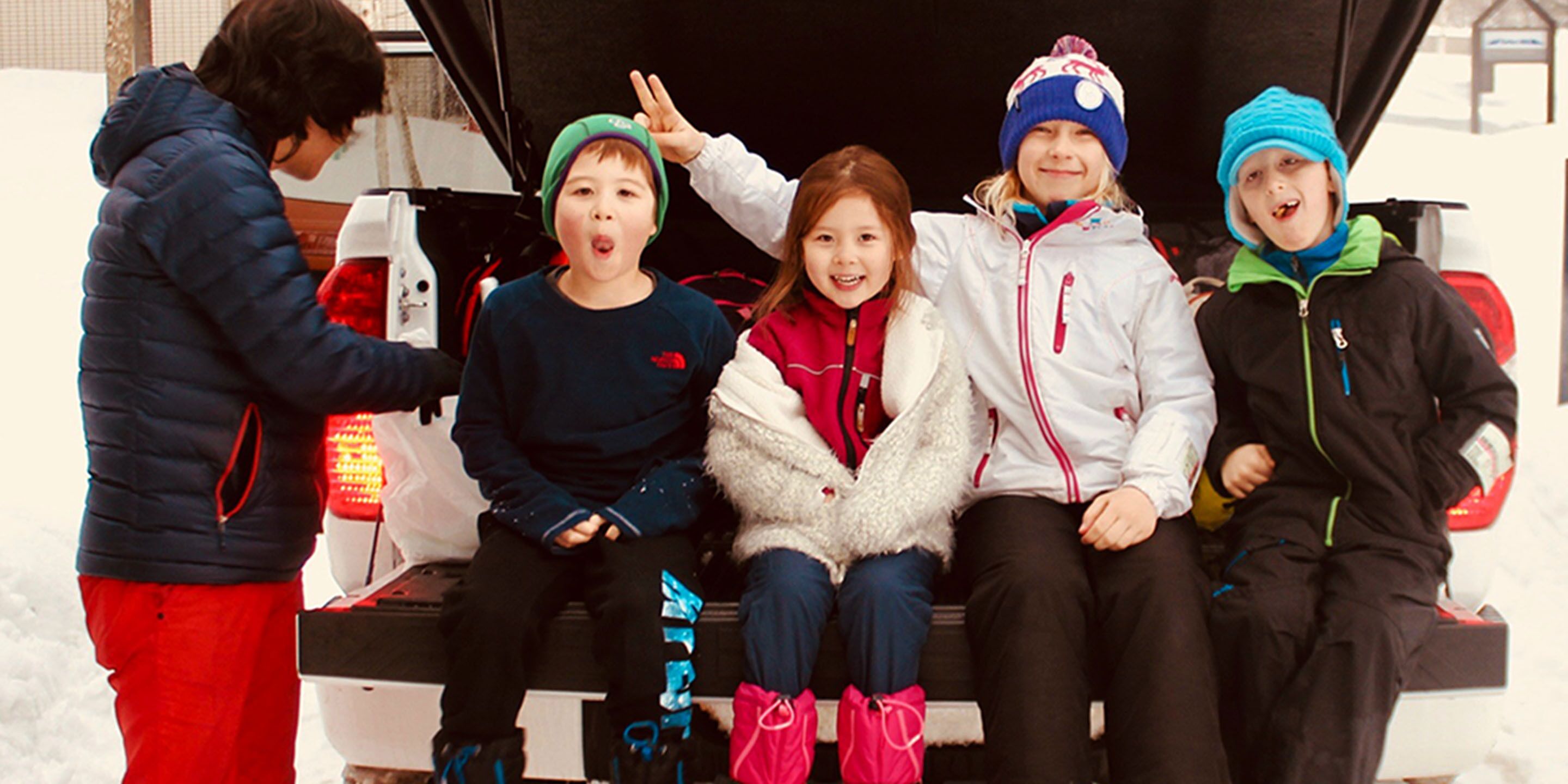 A group of people sitting in a vehicle with a snow-covered background.