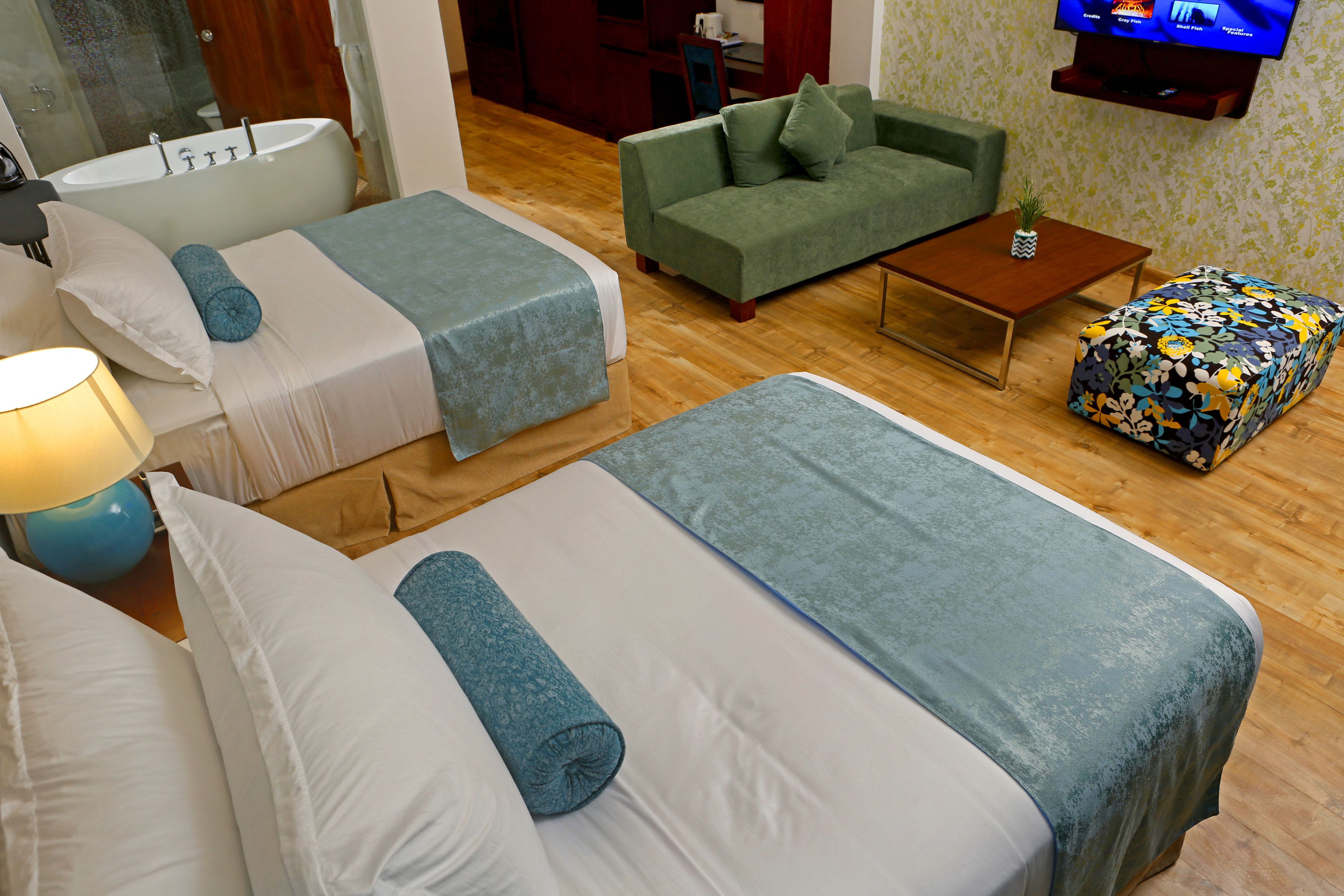 Une chambre d’hôtel avec deux lits, un canapé, une table basse et un téléviseur.