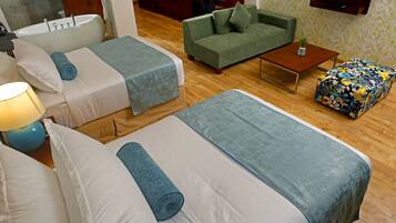 Une chambre d’hôtel avec deux lits, un canapé, une table basse et un téléviseur.