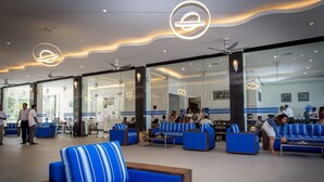 Eine großzügige Lobby mit blau-weiß gestreiften Sofas, einem Couchtisch und Deckenventilatoren.