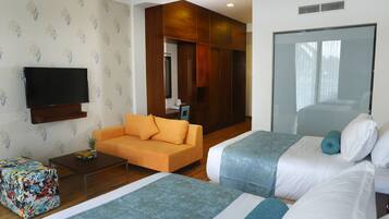 Quarto de hotel com duas camas, um sofá, uma televisão e um espelho.