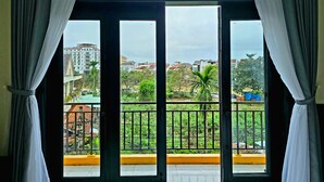 A room with a large window overlooking a balcony with a metal railing. - Flamingo Villa Hoi An (Da Nang)