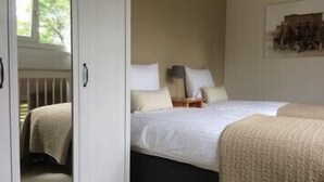 Un dormitorio con dos camas, una mesita de noche y una lámpara de pared.