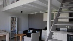 Una sala de estar moderna con una escalera, un sofá, una mesita y una estantería.