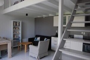 Una sala de estar moderna con una escalera, un sofá, una mesita y una estantería.