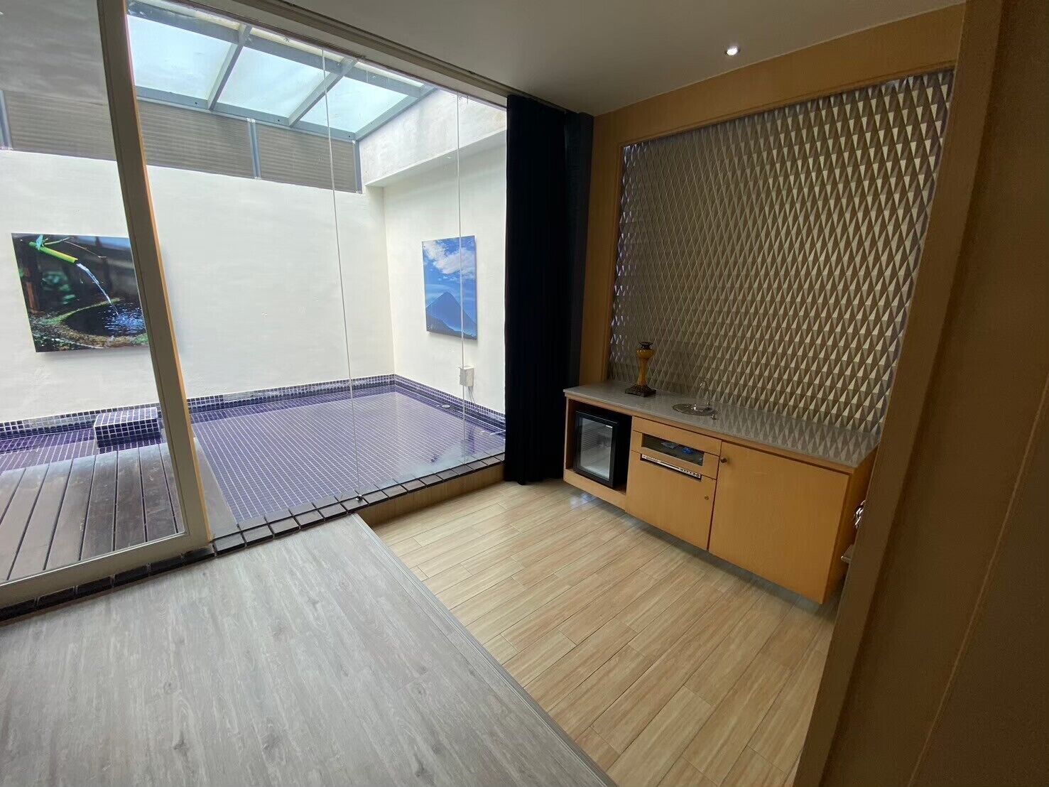 A modern bathroom with a glass shower enclosure, a wooden vanity, and a view of a pool area.