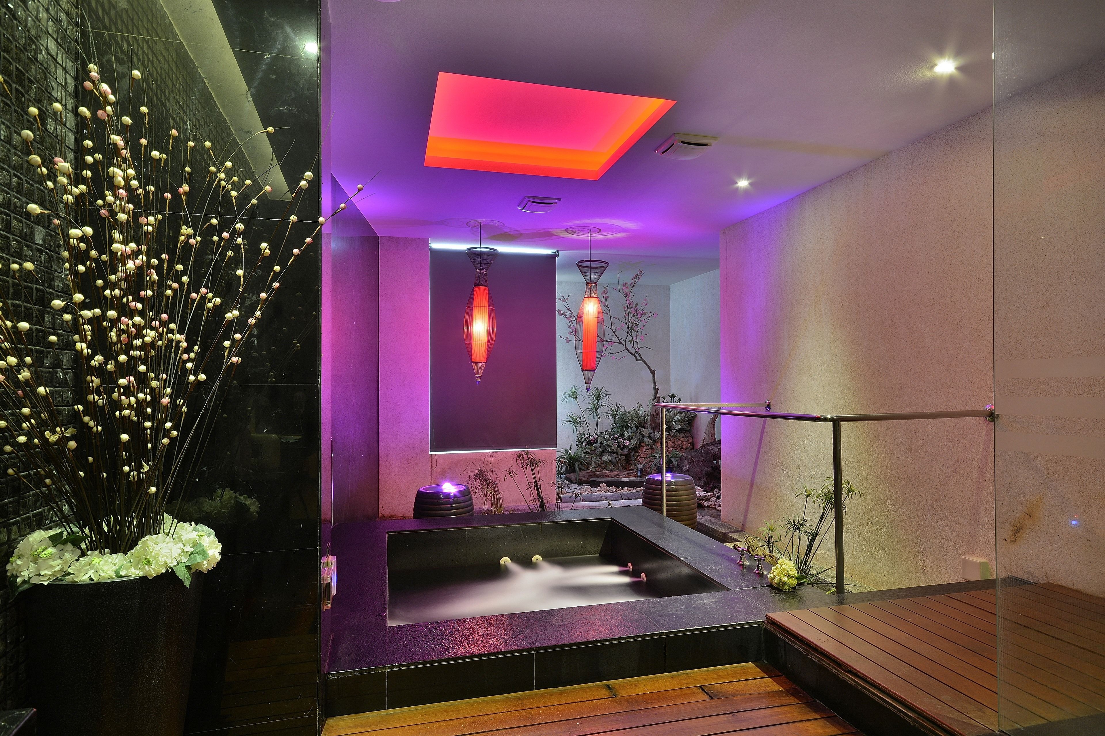 Un espace spa moderne doté d’un jacuzzi, d’un éclairage d’ambiance et de plantes décoratives.