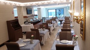 A restaurant with multiple tables set for dining, a buffet area, and a large window offering a view. - MB Deluxe Hotel (Istanbul)
