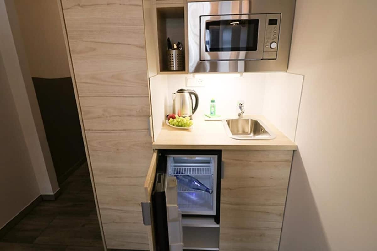 Eine kleine Küche mit integriertem Mikrowellenherd, Spüle und einem kleinen Kühlschrank.